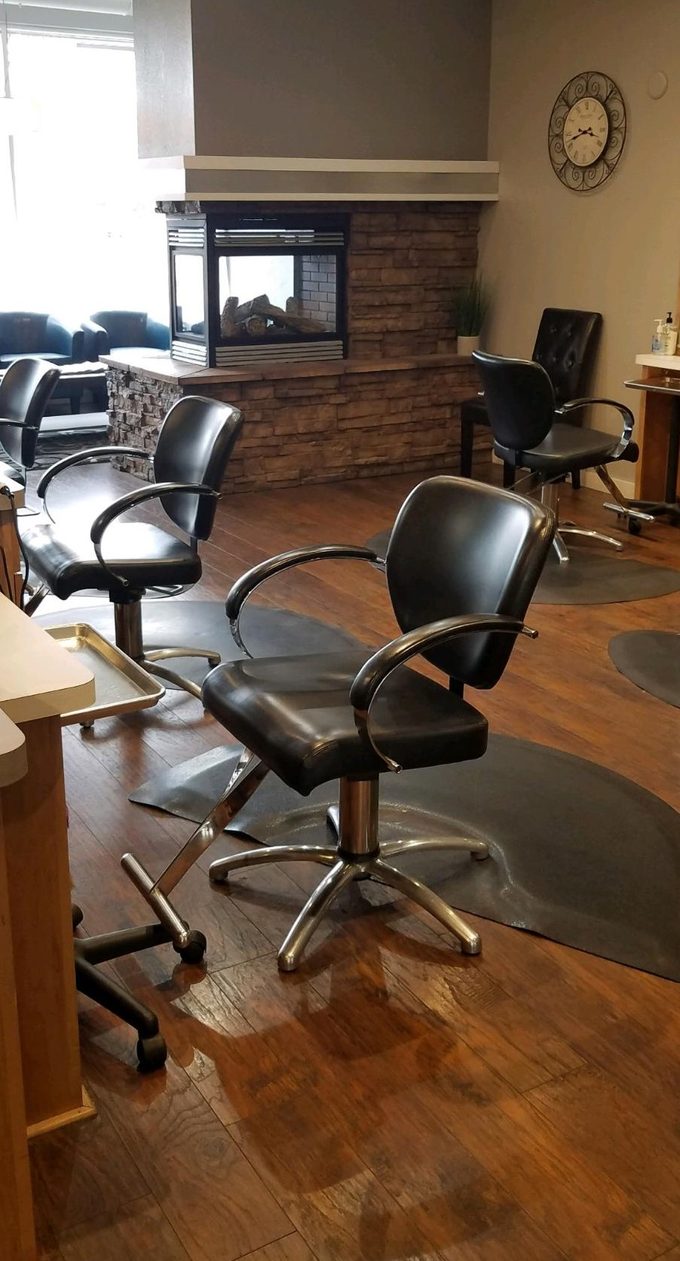 Black styling chairs in front of the two-sided stone fireplace at Urban Style Salon