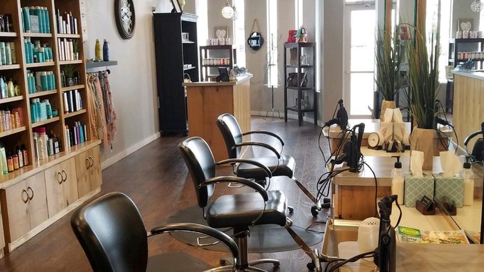 Inside Urban Style Salon: wood shelves of hair products beside a row of black styling chairs