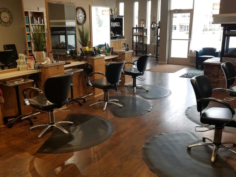 Styling stations and black chairs on the wood floor at Urban Style Salon, with the front windows behind